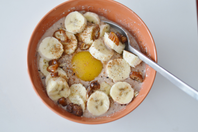warmer Frühstücksbrei von Alnatura mit Mandelmilch, einer Banane, einem Pfirsich, Erdnussmus (crunchy), Datteln, Kakao, Zimt und Vanille